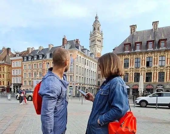 Deux enquêteurs consultent un indice sur leur téléphone, sur la Grand-Place de Lille, pendant une enquête en ville
